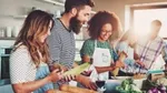 Five friends prepare pasta and vegetables in the kitchen