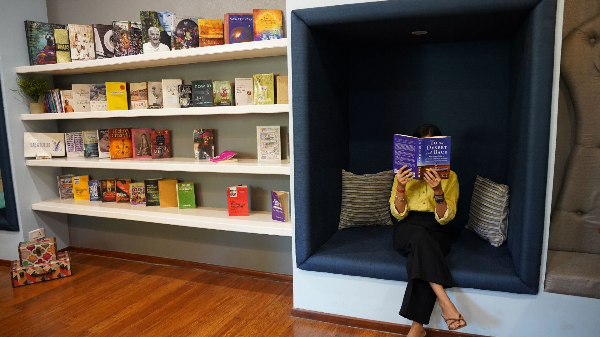 An Indian person sitting and reading a book in a bookstore.