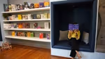 An Indian person sitting and reading a book in a bookstore.