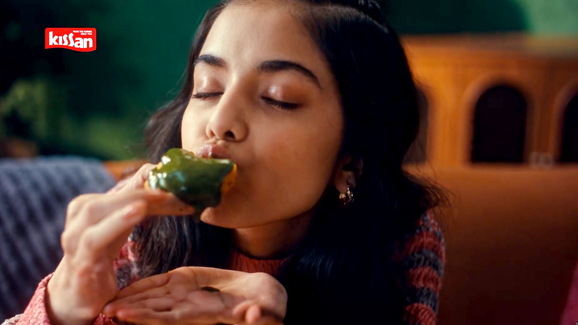 A key visual from the The Great Indian Chutneys TVC by Kissan.  The KV features a girl relishing green chutney on a piece of bread. 