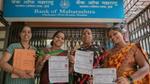 Four smiling Indian women showcase their Bank of Maharashtra loan documents outside the Ghatkopar branch in Mumbai, highlighting financial inclusion and women's empowerment.