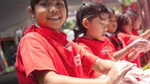 Smiling children wash their hands with Lifebuoy soap. They are wearing red T-shirts printed with a Lifebuoy logo.