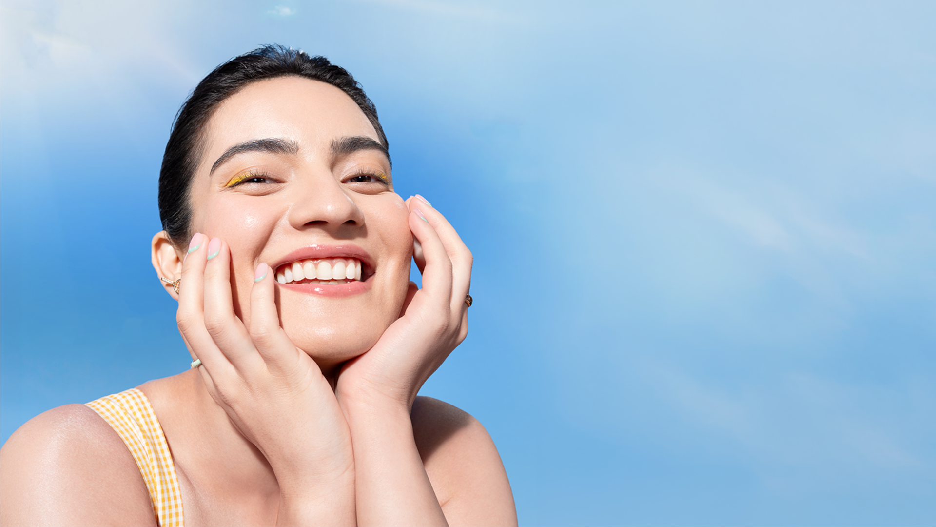 A person with a joyful expression, wearing a yellow outfit, smiles against a bright blue sky with a warm sunbeam.
