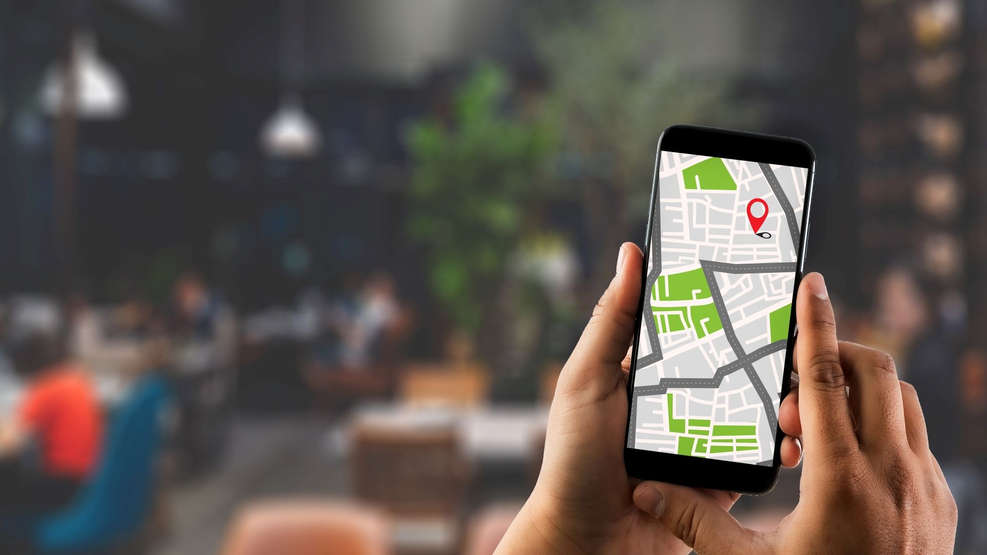 A person holding a mobile phone with the maps app open. The background is blurred out . 