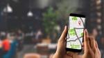 A person holding a mobile phone with the maps app open. The background is blurred out .