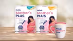 Two packs of Horlicks Mother's Plus nutrition drink in vanilla and kesar flavours featuring a pregnant woman in a pink dress, along with a filled mug displayed on a wooden surface.