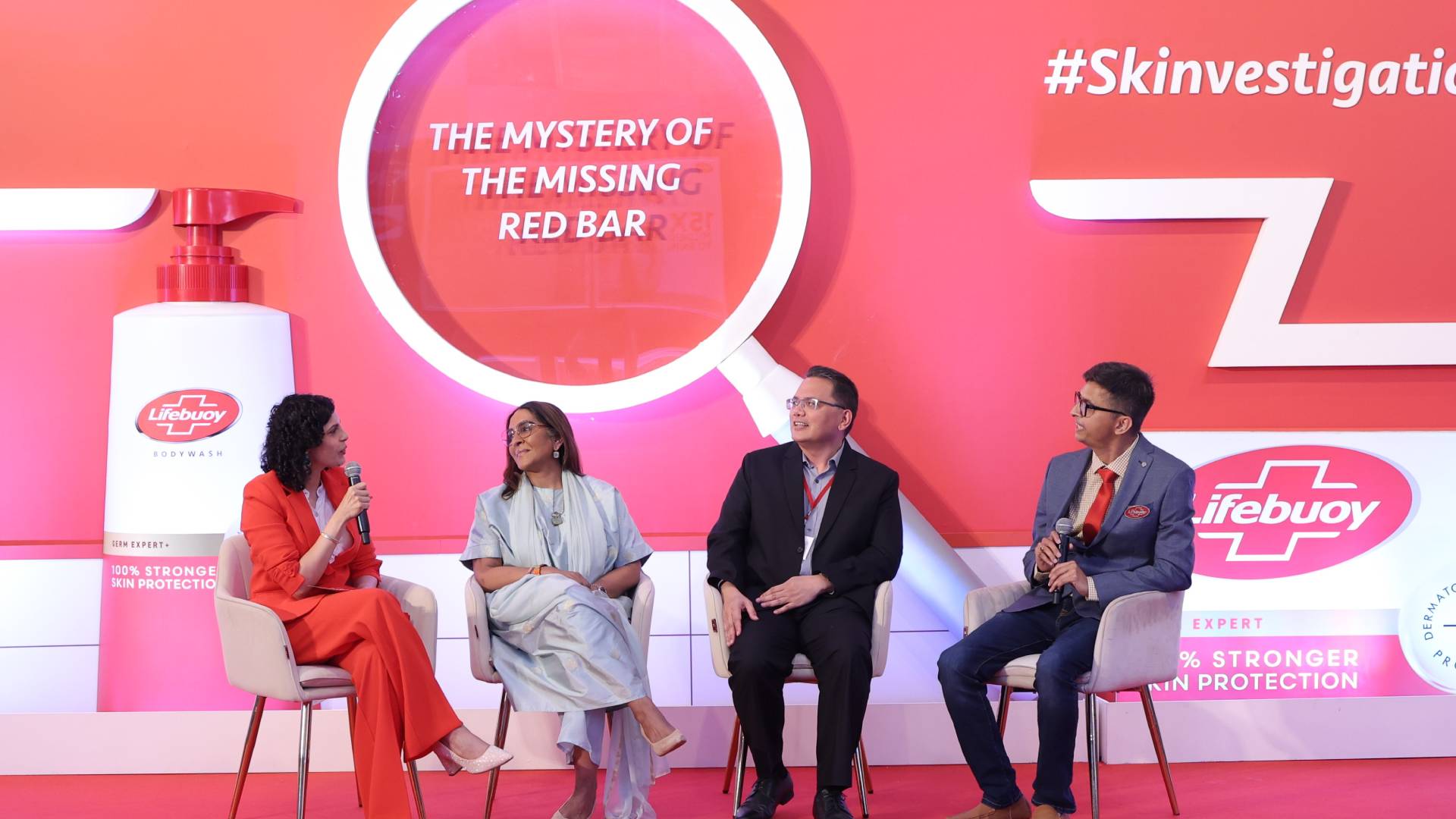 Four people seated on stage discussing under sign "The Mystery of the Missing Red Bar.