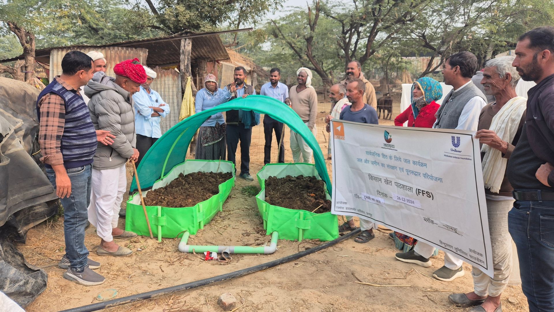 Rural farmers gather around covered compost beds during an outdoor agricultural training session.