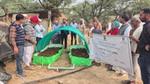 Rural farmers gather around covered compost beds during an outdoor agricultural training session.