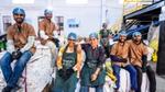 Waste processing team wearing protective hairnets poses together inside a recycling facility.