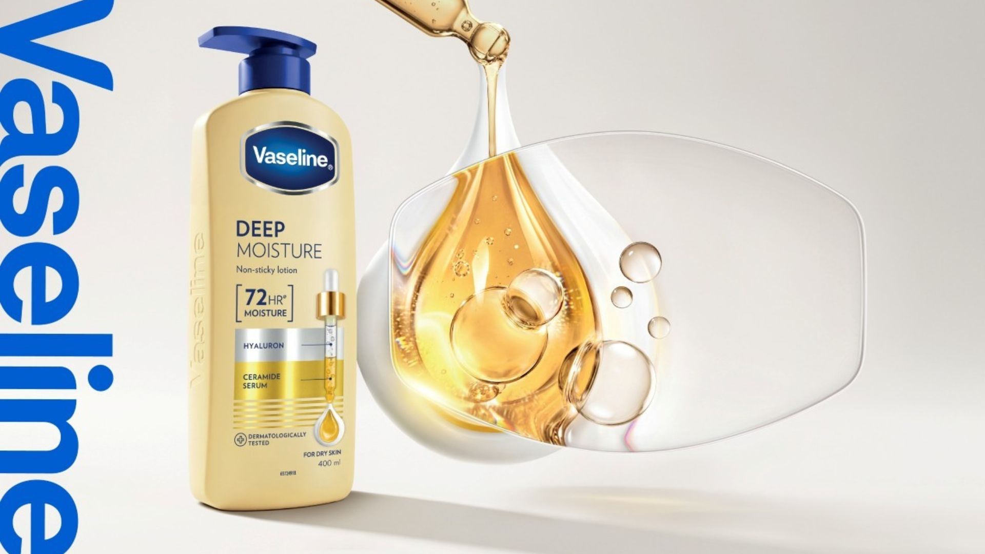 Vaseline Deep Moisture lotion bottle beside a golden serum droplet and clear bubbles.