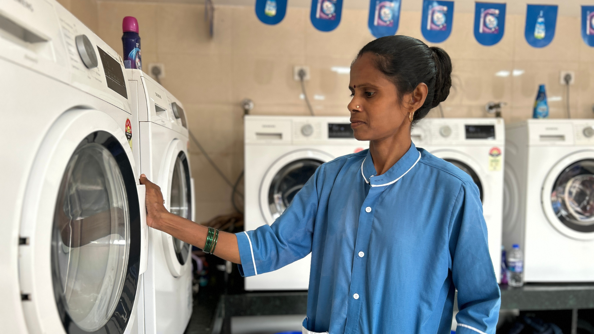 A Suvidha Centre worker using a washing machine at HUL Suvidha Centre