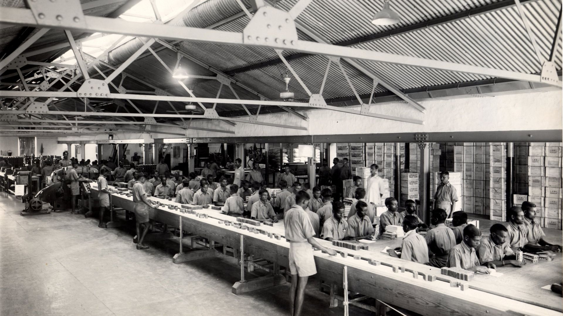 Workers operate a long production line in a large industrial factory.