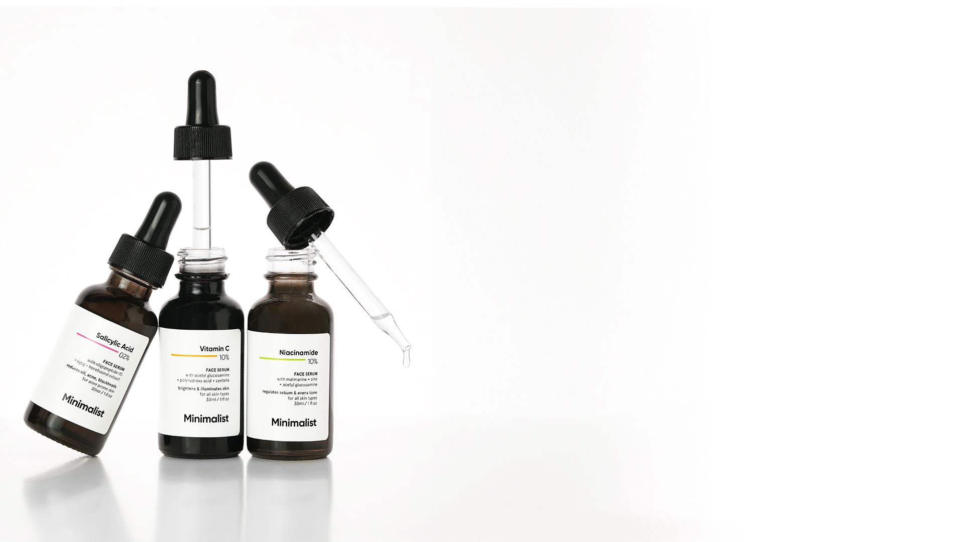 Three Minimalist skincare serum bottles with droppers arranged on a clean white background.