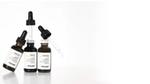 Three Minimalist skincare serum bottles with droppers arranged on a clean white background.