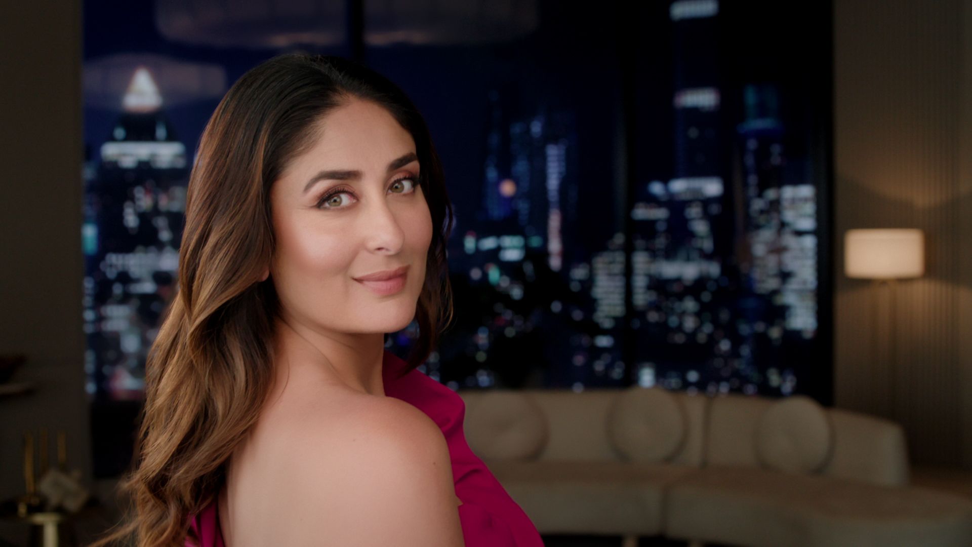 A woman looking at the camera with a city landscape in the background at night
