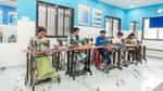 Women sewing at machines in a bright classroom.