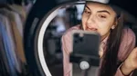 Woman filming herself with a smartphone and ring light