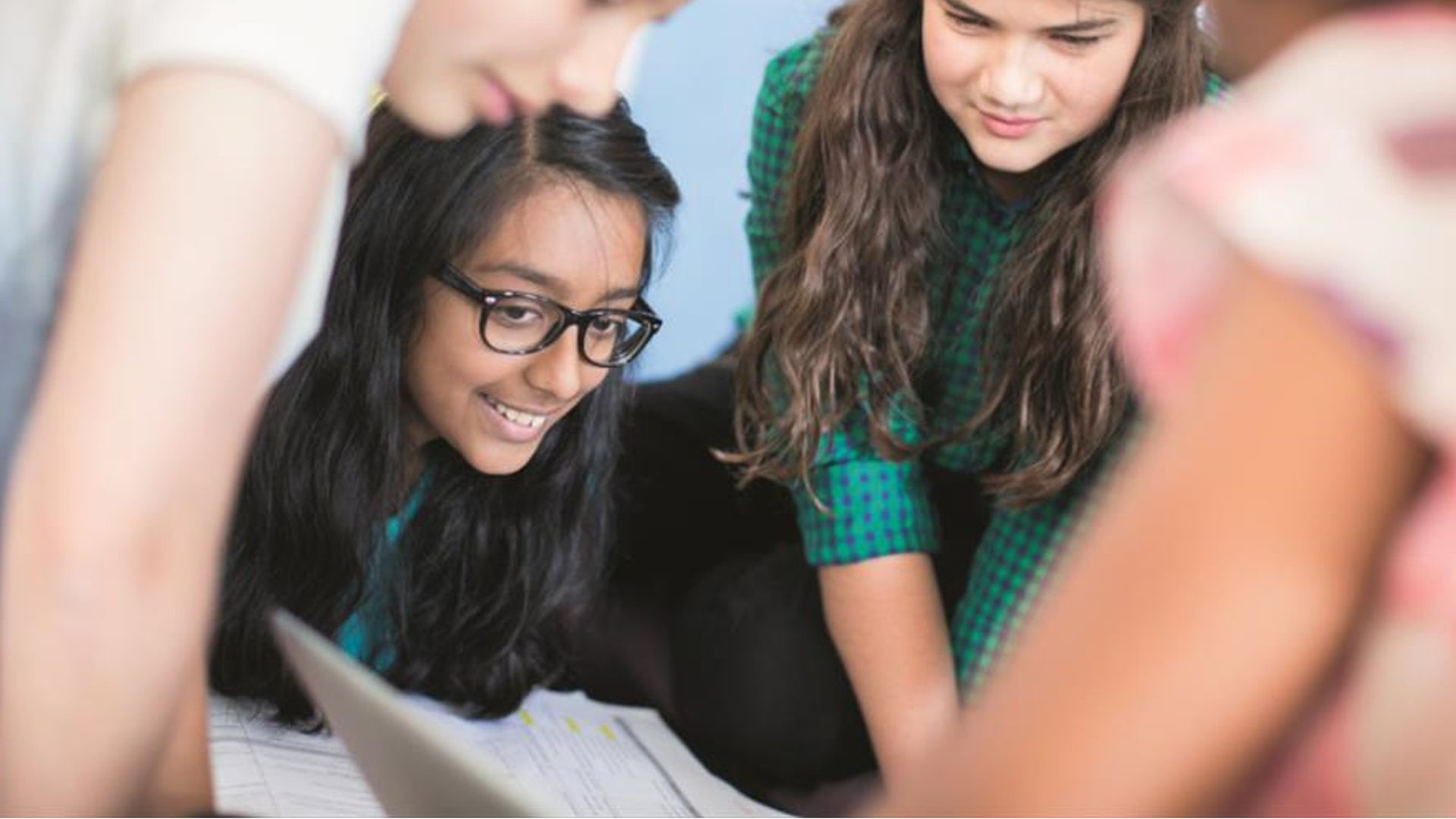 An image of a group of students looking at their books together. They seem to be involved in a discussion.  