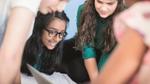 An image of a group of students looking at their books together. They seem to be involved in a discussion.