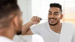 A man in white shirt brushing his teeth.