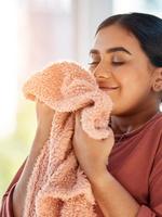 A woman smelling a peach-colored towel.