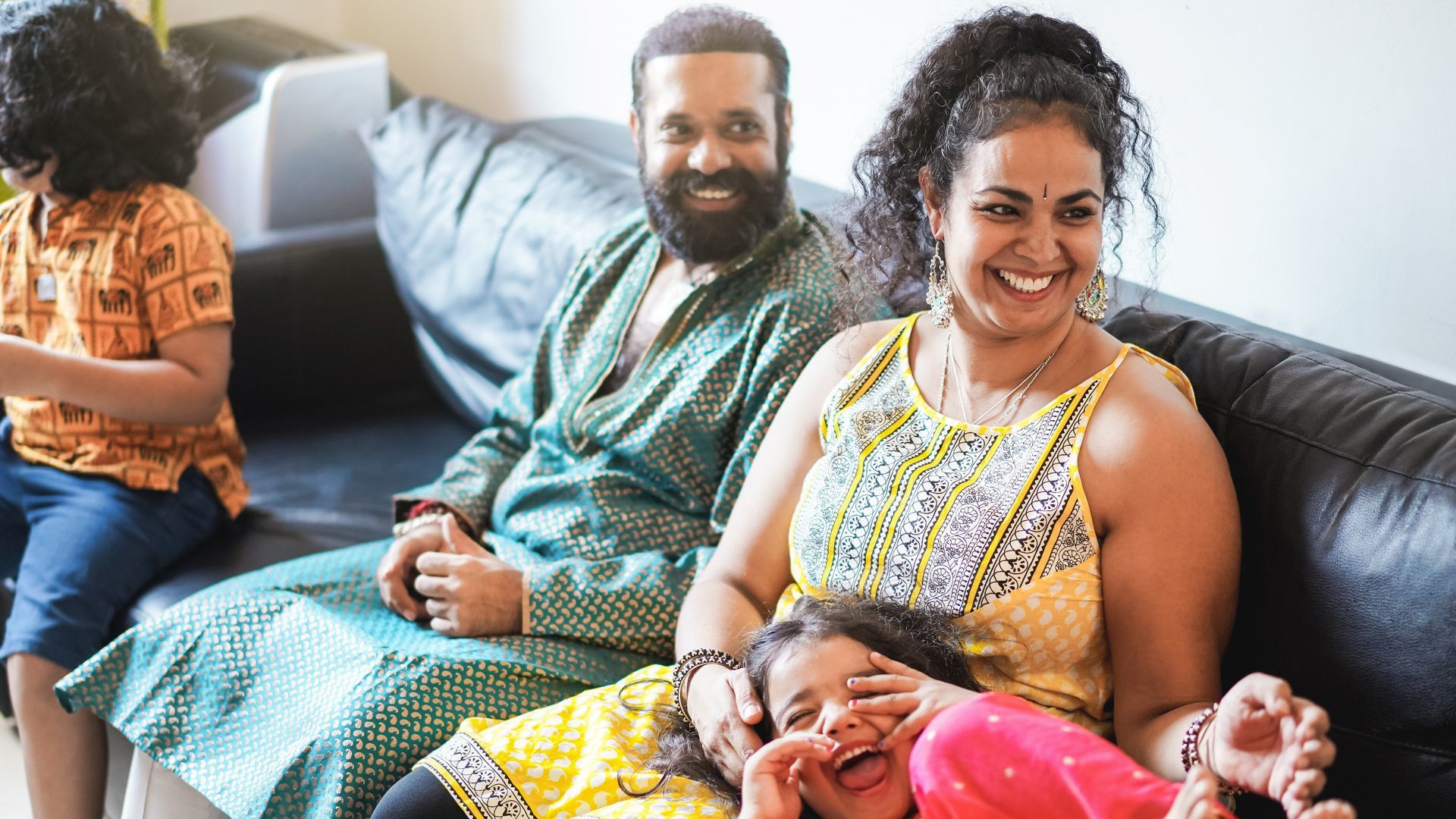 A group of people sitting on a couch, dressed in colorful attire.