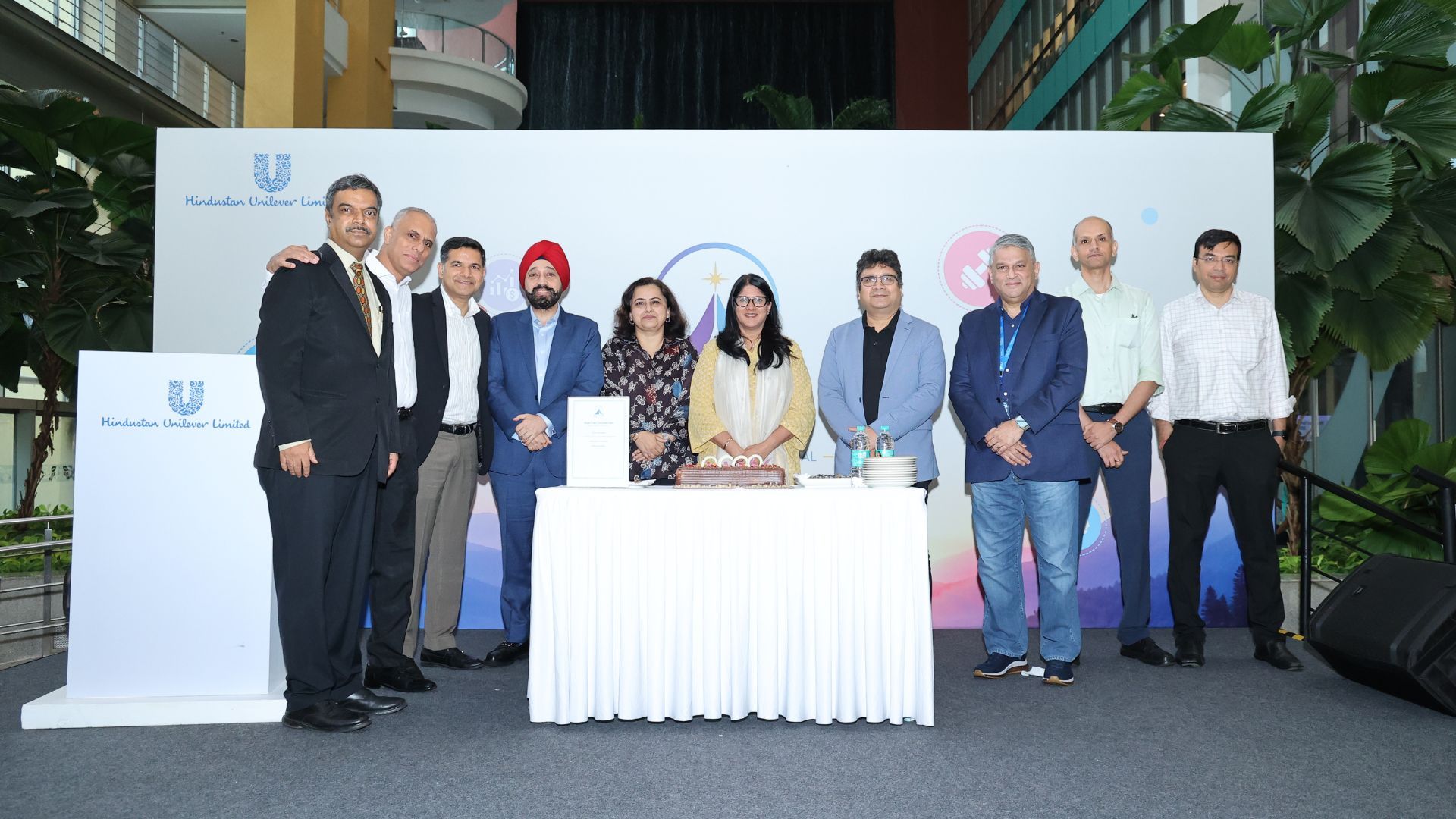 Corporate leaders stand behind a table with a cake at a Hindustan Unilever event.