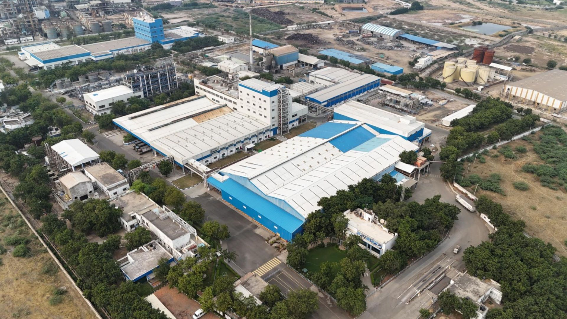 Aerial view of a large industrial complex surrounded by greenery and farmland.