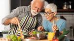 A man and woman preparing food in a kitchen from a recipe on a phone