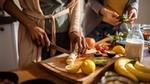 Close up shot of two pairs of hands preparing fruit and vegetables