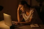 A picture of a lady in front of her laptop working in a dim light set up