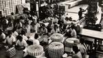 Workers package products along assembly lines in a busy factory.
