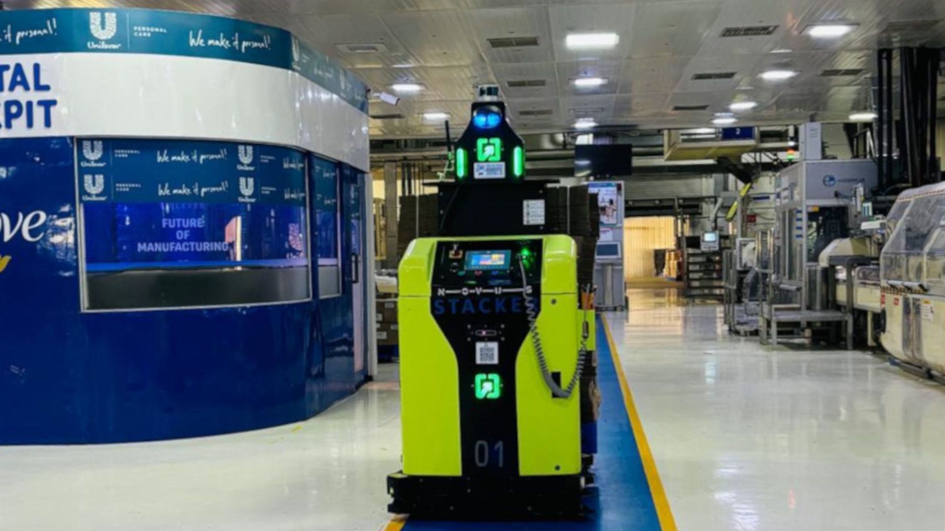 Autonomous warehouse robot driving along a blue lane inside a factory floor.