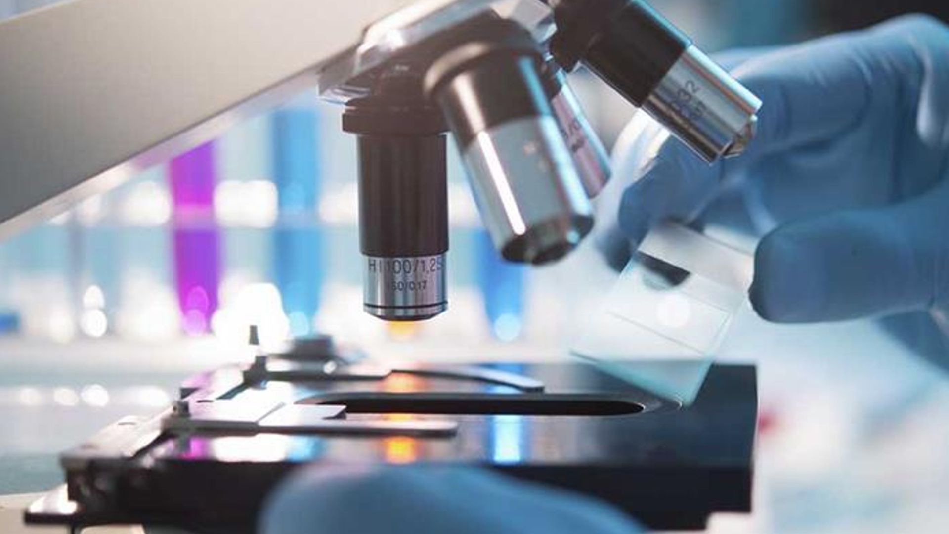 Image of an HUL employee’s hands placing a glass slab under a microscope. 