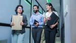 Three employees walking down an aisle in a corporate setting.
