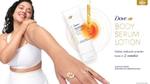 Smiling woman touches her smooth arm beside Dove Body Serum Lotion product packaging and dropper graphic
