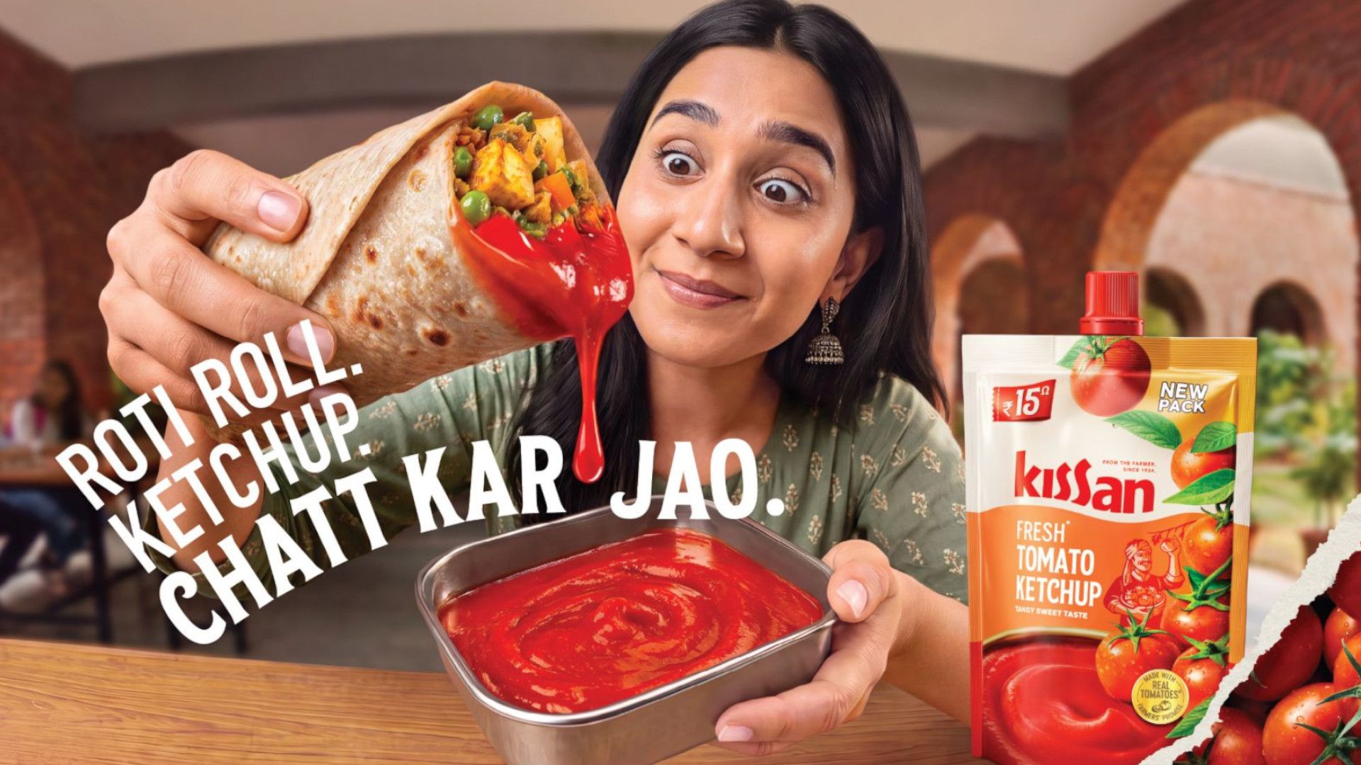 Woman pours Kissan tomato ketchup from a vegetable roti roll beside a ketchup pouch.