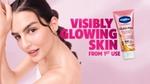 Woman beside Vaseline Gluta-Hya Dewy Radiance lotion with text promising visibly glowing skin from first use.
