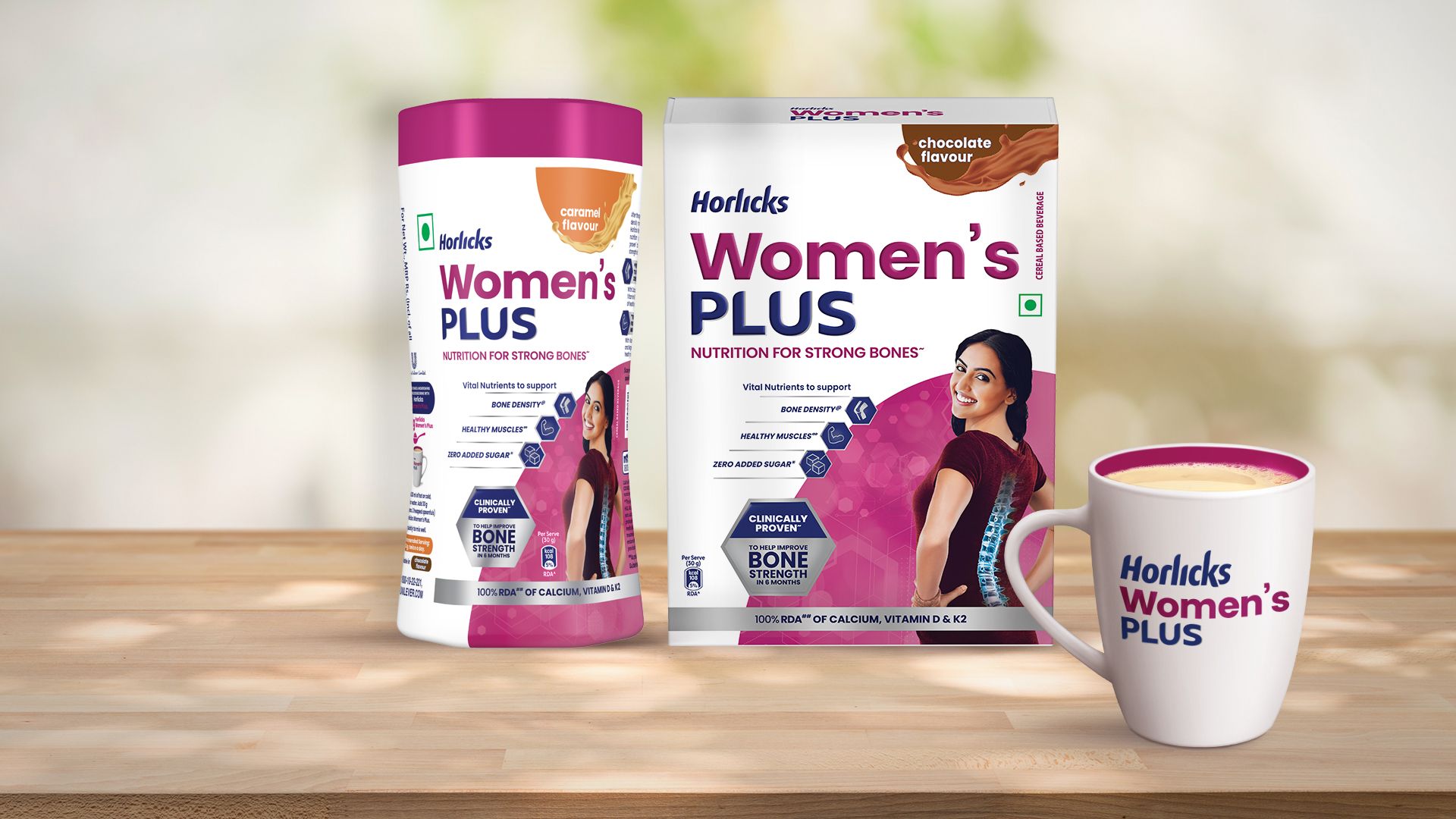 Two packs of Horlicks Women’s Plus packs in caramel and chocolate flavours featuring a woman with a spine illustration, along with a filled mug displayed on a wooden surface.