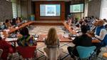 People attending a meeting in a conference room with a presentation on screen.