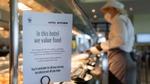 A chef working in a kitchen with a clear sign declaring that the kitchen works to ensure food is not wasted