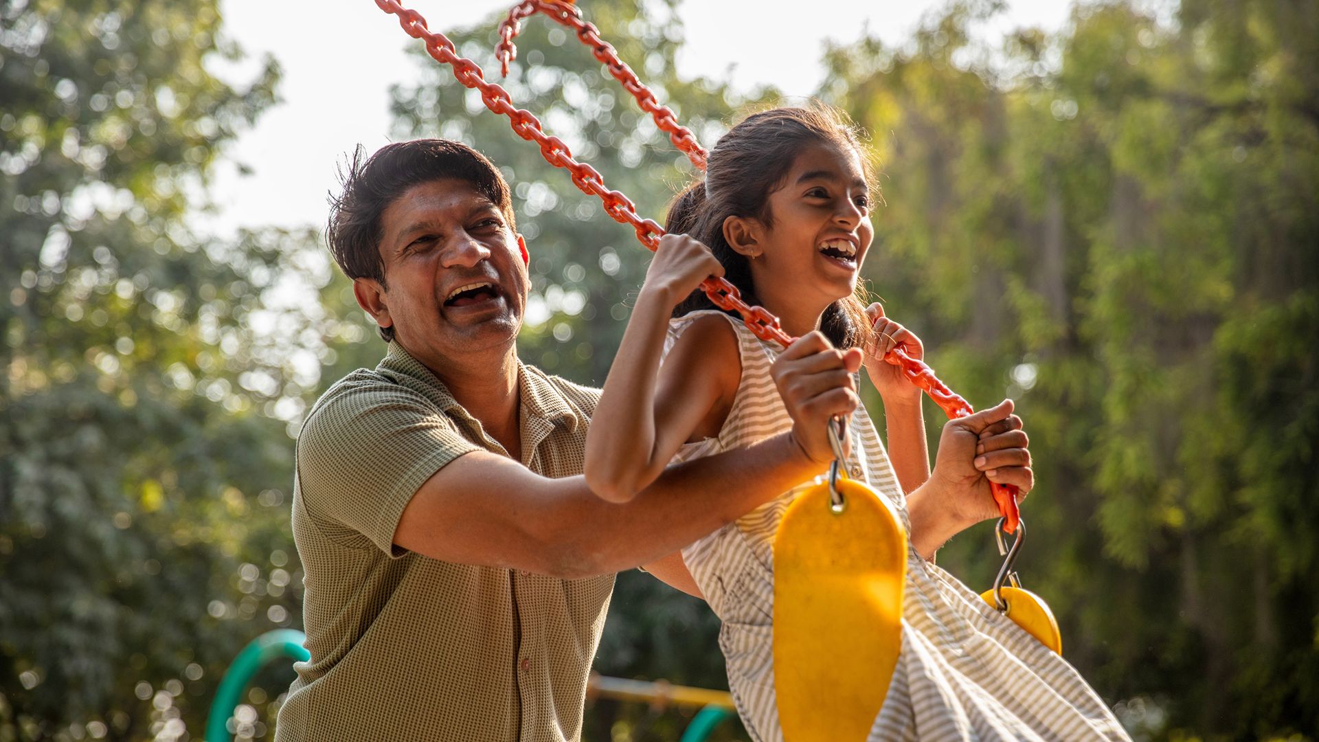 Two people on a swing in a park setting