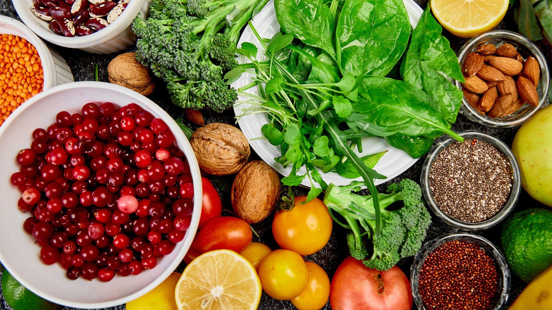 A colorful variety of fruits, vegetables, herbs, grains, nuts, and seeds laid out on a surface