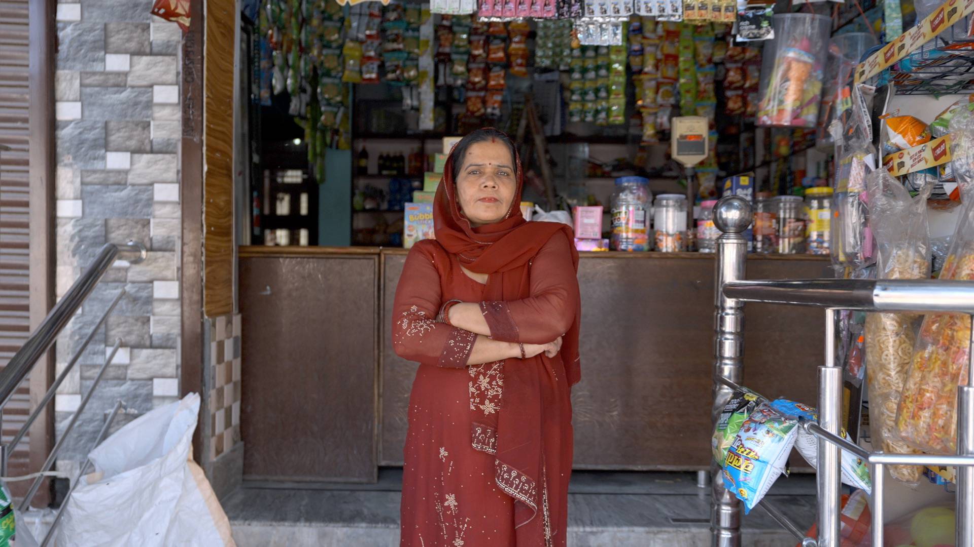 Woman in a red outfit standing in a small store entrance.