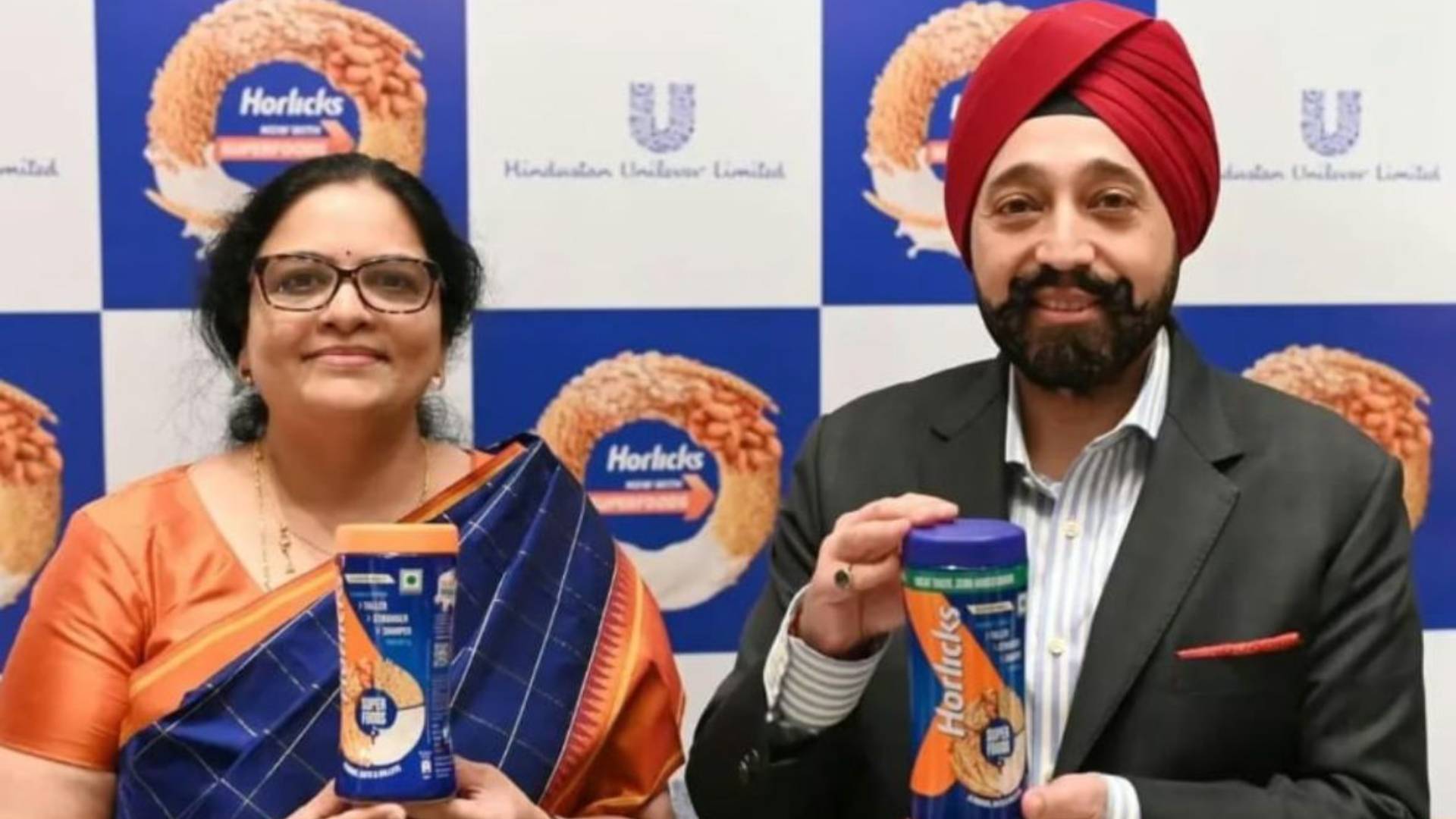 Two people holding Horlicks containers, Hindustan Unilever Limited backdrop.