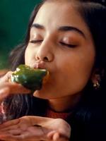 Person in a cozy sweater having a bite. Kissan logo in the top left corner.