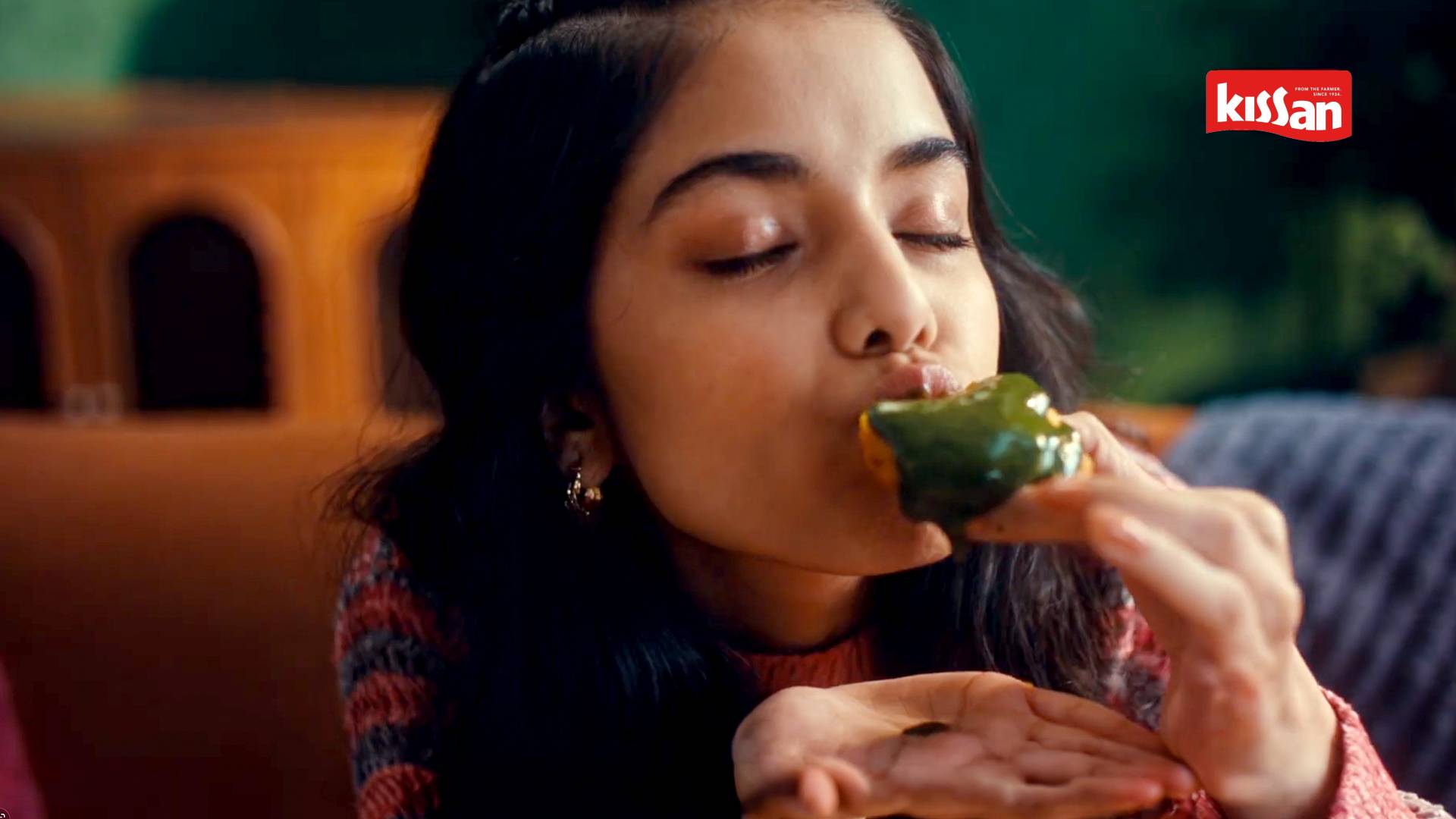A key visual from the The Great Indian Chutneys TVC by Kissan. The KV features a girl relishing green chutney on a piece of bread.