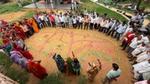 Community members stand in a circle outdoors, discussing a colorful map drawn on the ground.