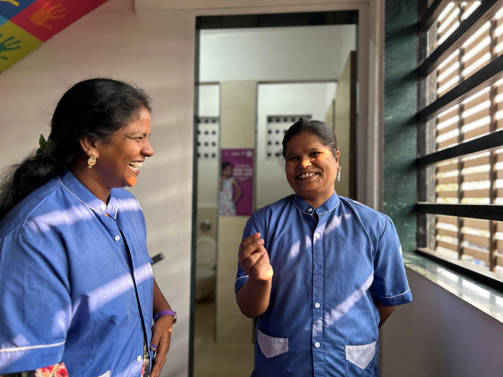 Two happy women outside a women's toilet.